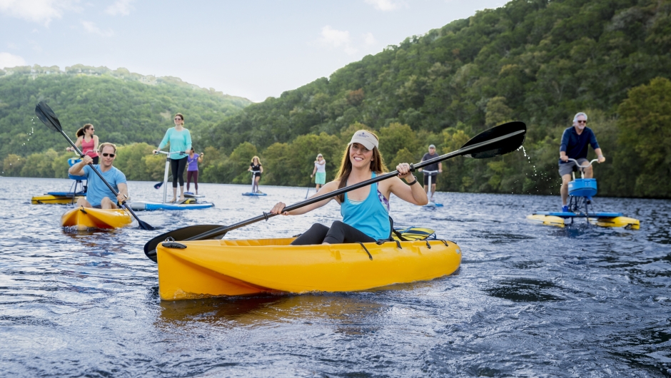 Group of people on the water in kayaks, paddleboards and different watercraft